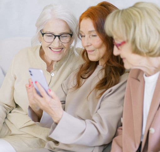 Three senior women having a video conference around a smartphone.